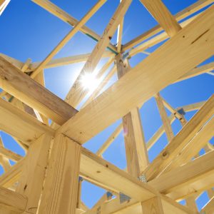 New residential construction home framing against a blue sky.